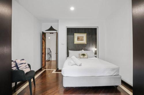 a bedroom with a white bed and a chair at Luxe Thirroul Home, Pool Spa Home Theatre in Thirroul