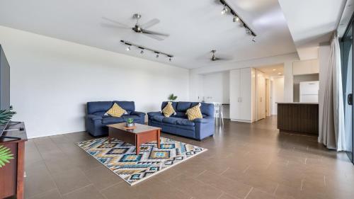 a living room with two blue couches and a table at Darwin Waterfront Short Stay Apartments in Darwin