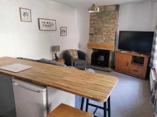 a living room with a table and a fireplace at Historic peaceful cottage in town centre! in Barnard Castle
