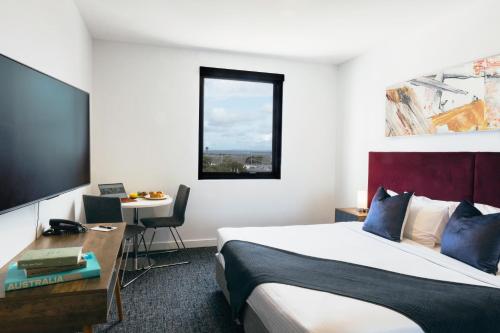 a hotel room with a large bed and a desk at Quest Mascot in Sydney