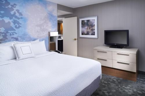 a bedroom with a white bed and a television at Courtyard Cleveland Airport North in North Olmsted