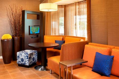 a waiting room with orange chairs and a table at Courtyard Cleveland Airport North in North Olmsted