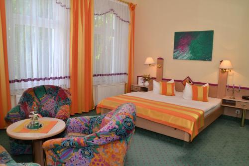 a hotel room with a bed and two chairs at Parkhotel Helene in Bad Elster