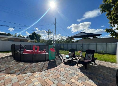 a backyard with a hot tub with two chairs and a table at Flamingo Paradise in Hialeah