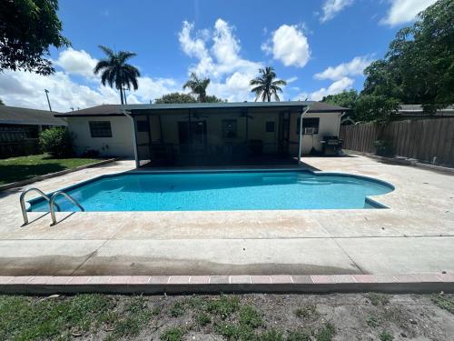 a swimming pool in front of a house at Whole House+Renovated+Pool+Lanai+BBQ+Close to All in West Palm Beach