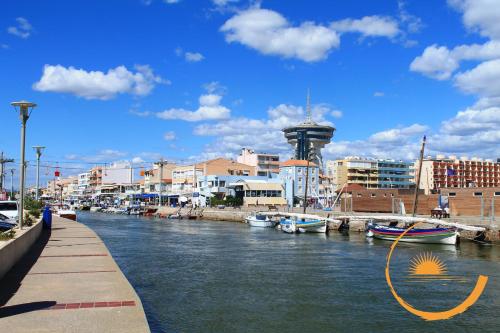 une rivière avec des bateaux amarrés dans une ville avec des bâtiments dans l'établissement Le Grand Bleu, La Grande Motte, Plage, à La Grande Motte