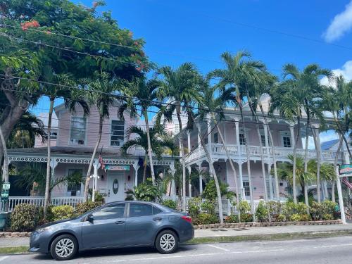 a car parked in front of a house with palm trees at The Palms Hotel in Key West