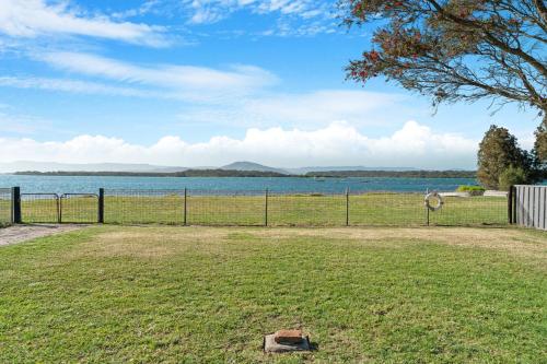 a field with a fence and a body of water at Sea Breeze Escape - Pet-Friendly Escape - Book 3, Pay for 2! in Greenwell Point