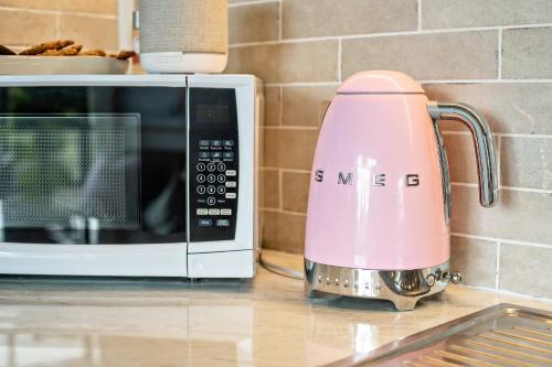 a pink mixer on a counter next to a microwave at Charming Hideaway Apartment Near St Kilda in Melbourne
