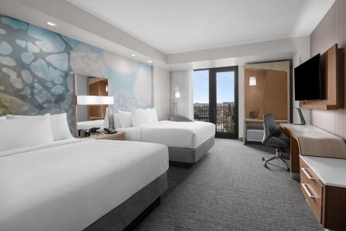a hotel room with two beds and a desk at Courtyard by Marriott Clearwater Beach in Clearwater Beach