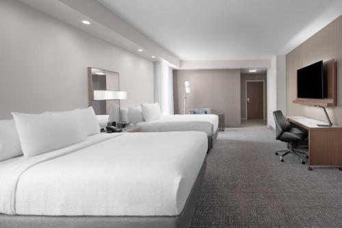 a hotel room with two beds and a desk at Courtyard by Marriott Clearwater Beach in Clearwater Beach
