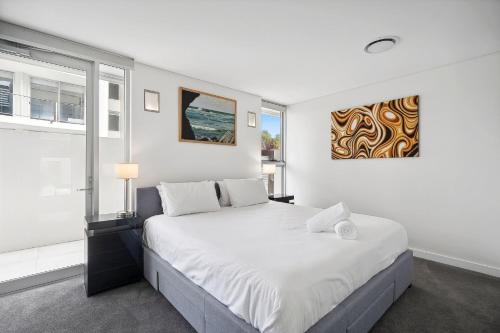 a white bedroom with a large bed and a window at Ramada By Wyndham Marcoola Beach in Marcoola