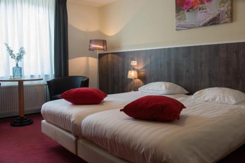 a hotel room with a large bed with red pillows at Landgoed Ehzerwold in Almen