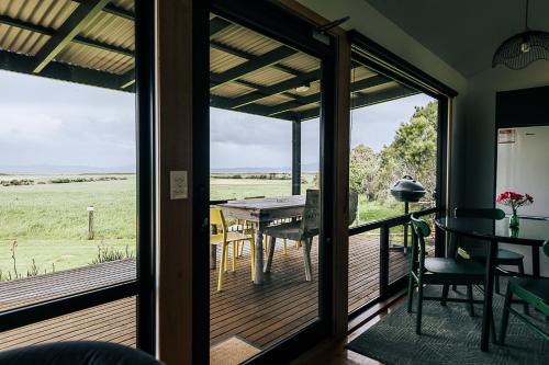 a screened in porch with a table and chairs at Black Cockatoo Cottages in Yanakie