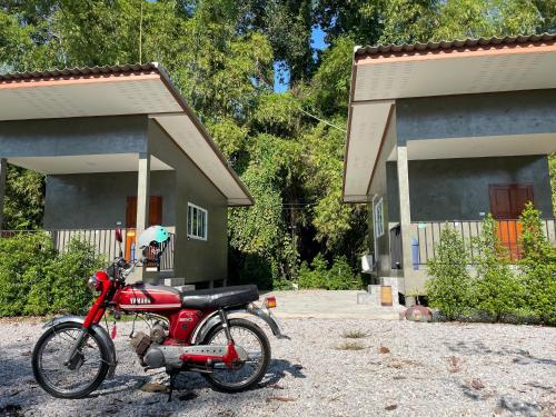 a red motorcycle parked in front of a building at บ้านอยู่ดีโฮมสเตย์ in Ban Hua Khao