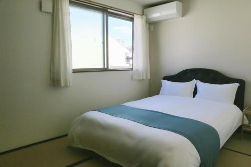 a bedroom with a large bed with a window at 雅舍12 Osaka house new open一軒家貸切 in Osaka