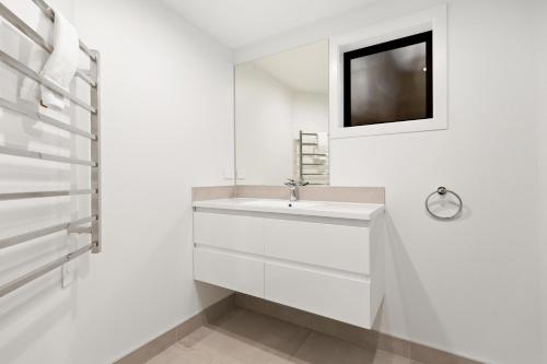 a white bathroom with a sink and a tv at Lodges 6 - Lake views and close to town in Queenstown