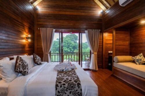 a bedroom with a large bed and a large window at Lembongan Cempaka Villa & Restaurant in Nusa Lembongan
