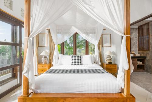 a bedroom with a canopy bed and a window at Umah Bali Villa in Ubud