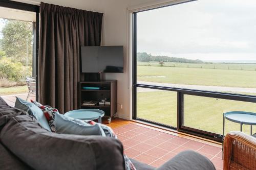a living room with a couch and a large window at Black Cockatoo Cottages in Yanakie