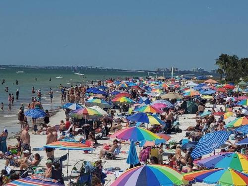 a large crowd of people on a beach with umbrellas at DOWNTOWN 3rd Street Retreat Lookout in Fort Myers Beach