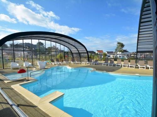 une grande piscine avec des chaises et un bâtiment dans l'établissement Mobil-home Grand Confort 2 Chambres, Proche Plage, 4 Pers., Piscine Chauffée, Parking, Wi-Fi Gratuit - FR-1-361A-86, à Jullouville
