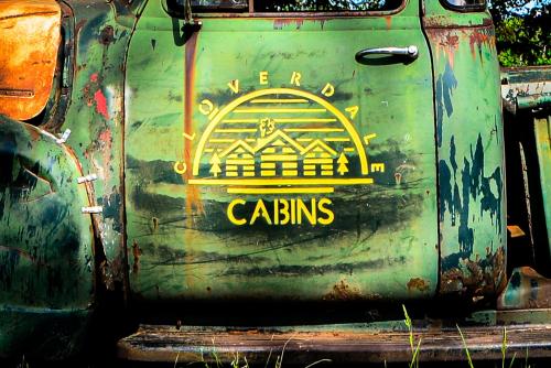 a green door with a yellow logo on it at Cozy Cabin with Hottub at Cloverdale Cabins in Hinckley