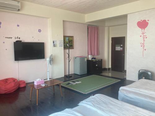 a living room with a bed and a flat screen tv at 福田民宿 台東民宿476號 in Guanshan