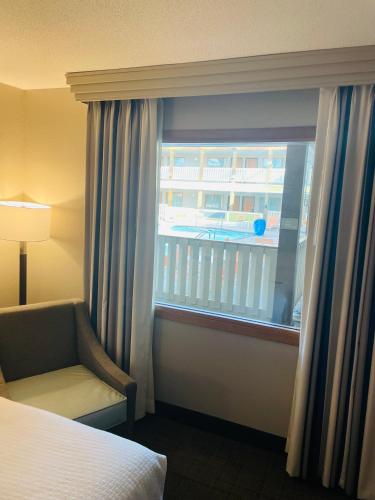 a hotel room with a window with a bed and a chair at Best Western Plus Dubuque Hotel and Conference Center in Dubuque