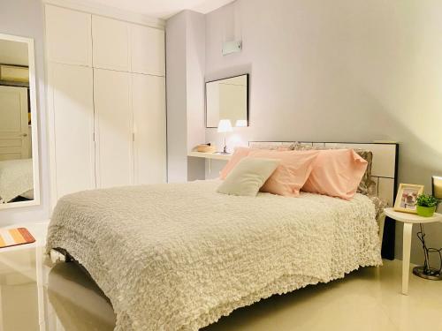a white bedroom with a bed with pink pillows at Cozy 1br walk to BTS and Airport Rail Link Close to Malls 11 in Bangkok