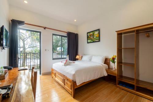 a bedroom with a bed and a desk and a window at Aurora House in Phu Quoc
