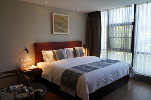 a bedroom with a large bed and a window at 重庆文里苗品茶艺术酒店Chongqing Jiangbei Airport Creative Park Store in Renhe