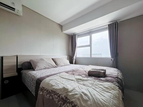 a bedroom with a large bed and a window at MODERN Trivium Apt 1BR with Wi-Fi, Pool and Gym by 2ndHome in Jatirarangan