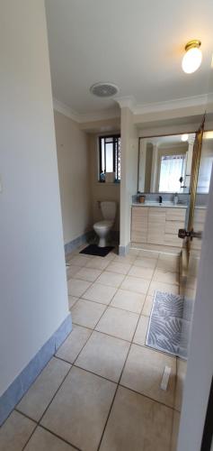 a bathroom with a toilet and a sink and a mirror at Gold Coast Family Retreat, beach 1 and half kms, shops, full home in Gold Coast