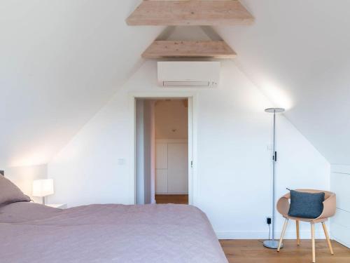 an attic bedroom with a bed and a chair at Premium Ferienhaus Söss Diek in Groß Schwansee in Kalkhorst