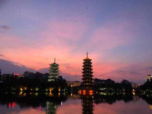 two towers in the water with a sunset at Guilin Bonjour Boutique Hotel- Free pick up service over 3 nights in Guilin