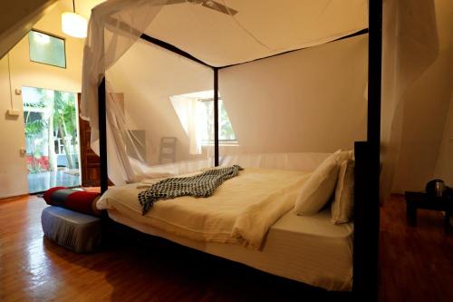 a bedroom with a canopy bed in a room at Temple Garden Palolem in Canacona