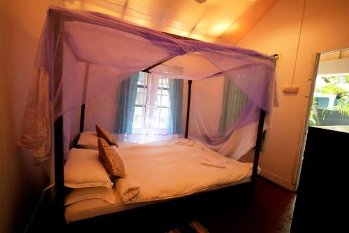 a canopy bed in a room with a window at Temple Garden Palolem in Canacona