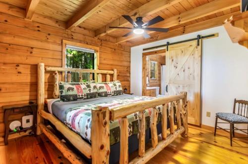 a log cabin bedroom with a bed and a ceiling fan at Mountain View, hot tub, fire pit, game room in Blairsville