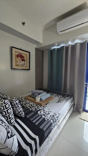 a bedroom with a large bed with black and white pillows at Sea Residences TowerE-F by EZStays in Manila