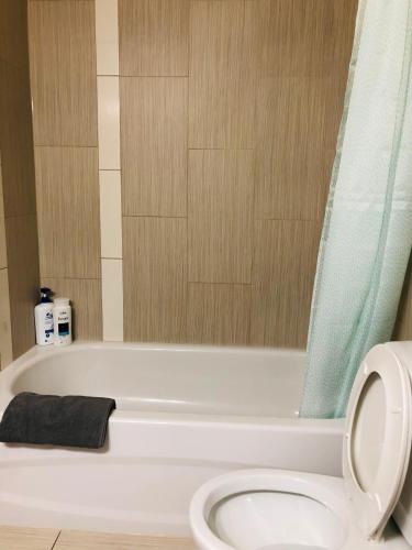 a bathroom with a white tub and a toilet at 5th Floor 1-Bedroom Condo with Parking in Calgary