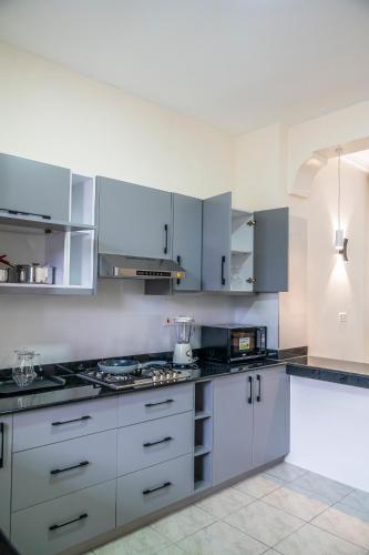 a kitchen with white cabinets and a stove top oven at Leshan Luxury Villas in Diani Beach