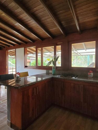 a large kitchen with wooden cabinets and a large island at La Pascana Ecolodge frente al parque Arví Entorno natural excepcional, reserva natural, áreas protegidas, conexión con la naturaleza y avistamiento de aves a 3km del metrocable Guarne in Guarne