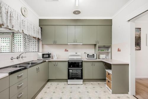 a kitchen with green cabinets and white appliances at Jetty Road Retreat - Brighton - C21 SouthCoast Holidays in Brighton