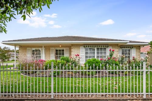 a white picket fence in front of a house at Jetty Road Retreat - Brighton - C21 SouthCoast Holidays in Brighton