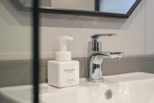 a bottle of soap sitting on a bathroom sink at Rose Bay Hotel in Busan