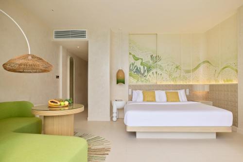 a bedroom with a bed and a green chair at Centara Mirage Lagoon Maldives in Nakachchafushi