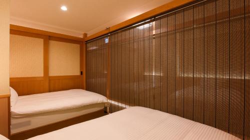a small room with two beds and a closet at YOKOHAMA STAY PREMIER in Yokohama