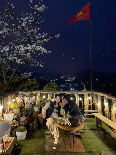 two people are sitting at a table at night at Đồi Thông Homestay Mộc Châu - by BAY LUXURY in Sơn La
