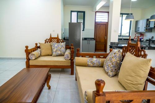 a living room with couches and a table and a kitchen at Leshan Luxury Villas in Diani Beach